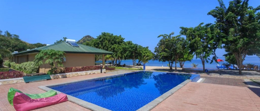 A beautiful swimming pool at a tropical resort with a beach and ocean in Labuan Bajo, Indonesia.