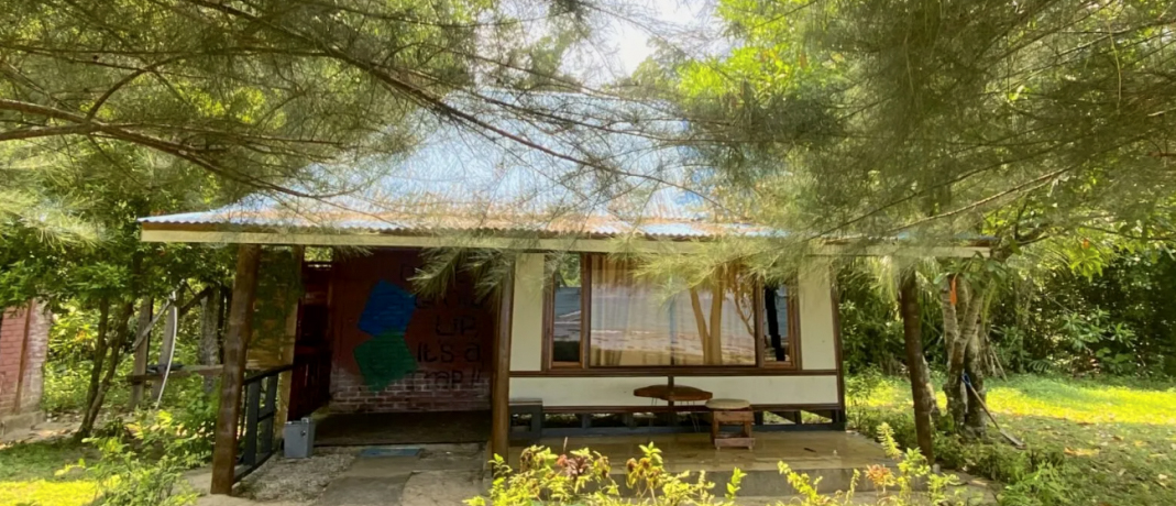 A rustic beach hut with a corrugated roof nestled among trees in Sungai Pinang.