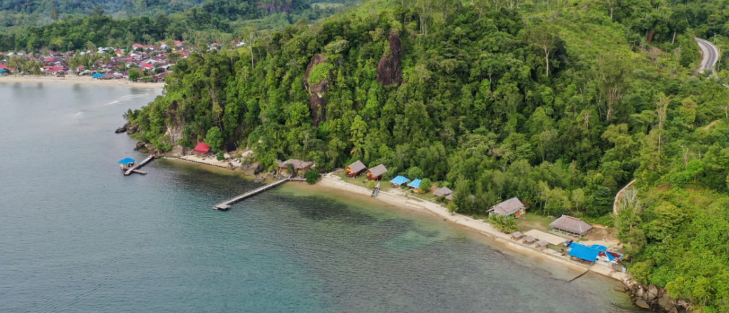 Quiet coastal village with rustic beach huts, piers, and jungle-covered hills in Sungai Pinang.