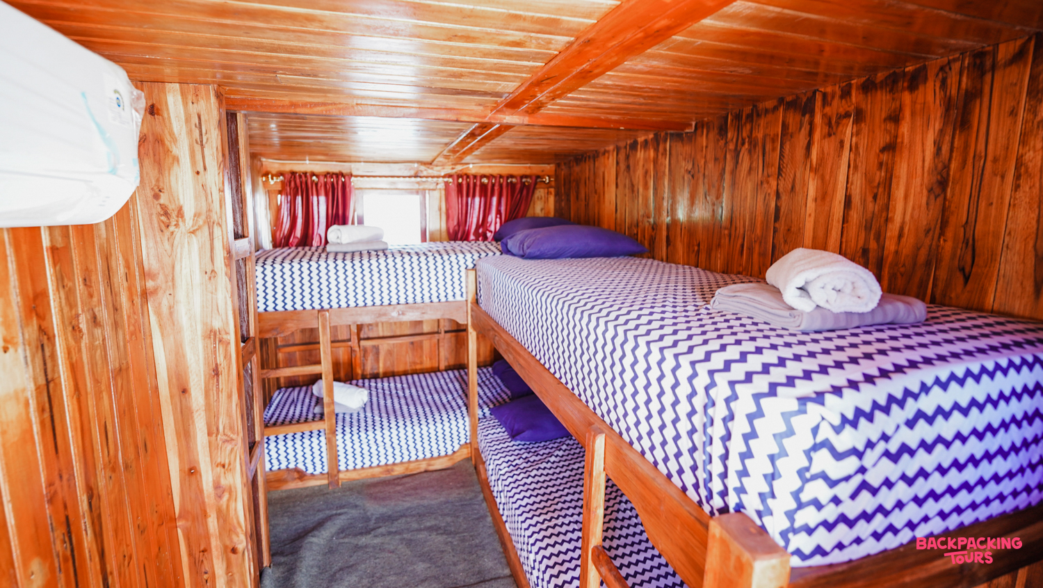 Cozy wooden cabin on a live-aboard boat featuring two sets of bunk beds with fresh linen.