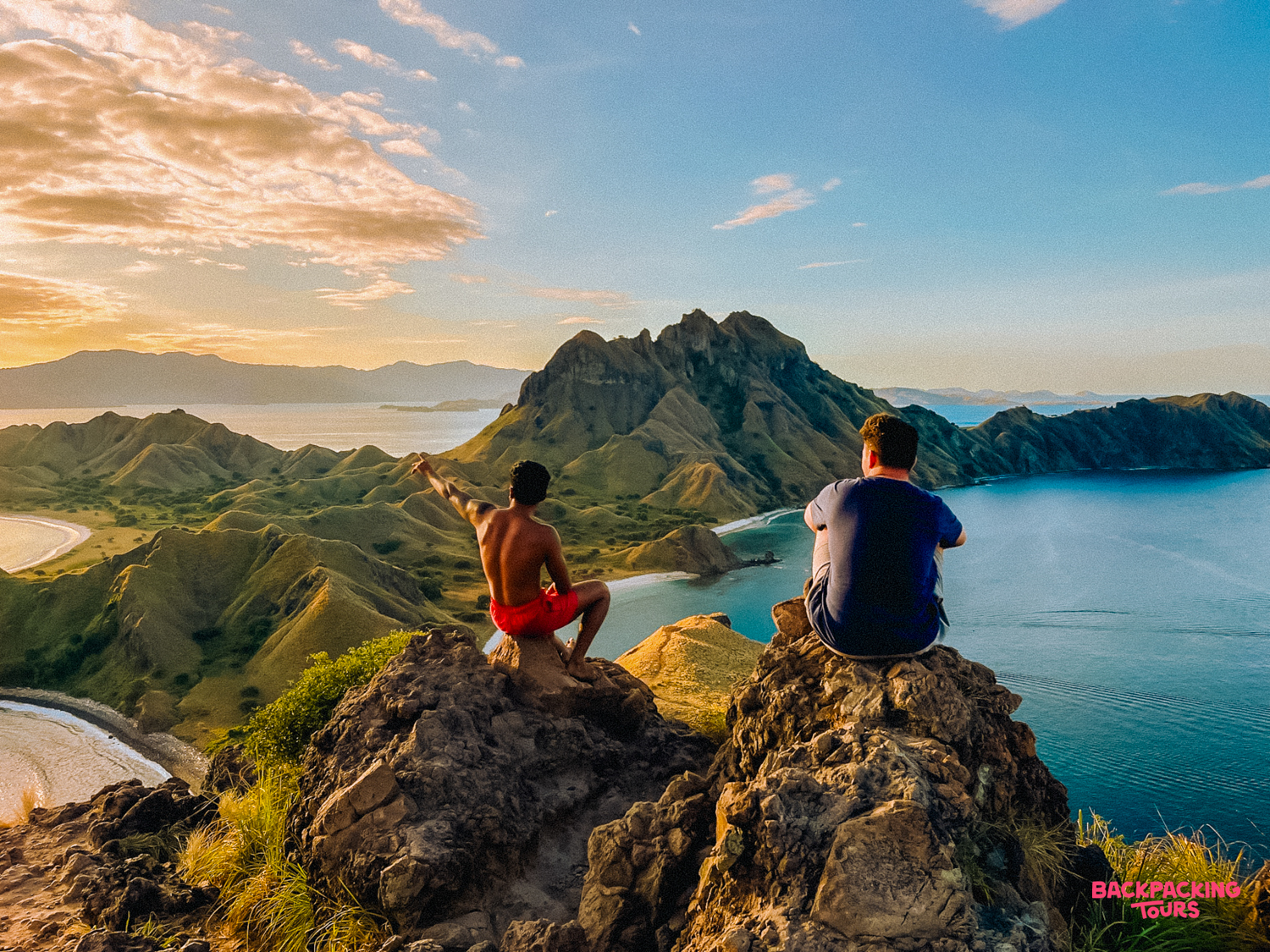 Adventurers watch a beautiful sunset over the iconic bays of Padar Island, Indonesia.