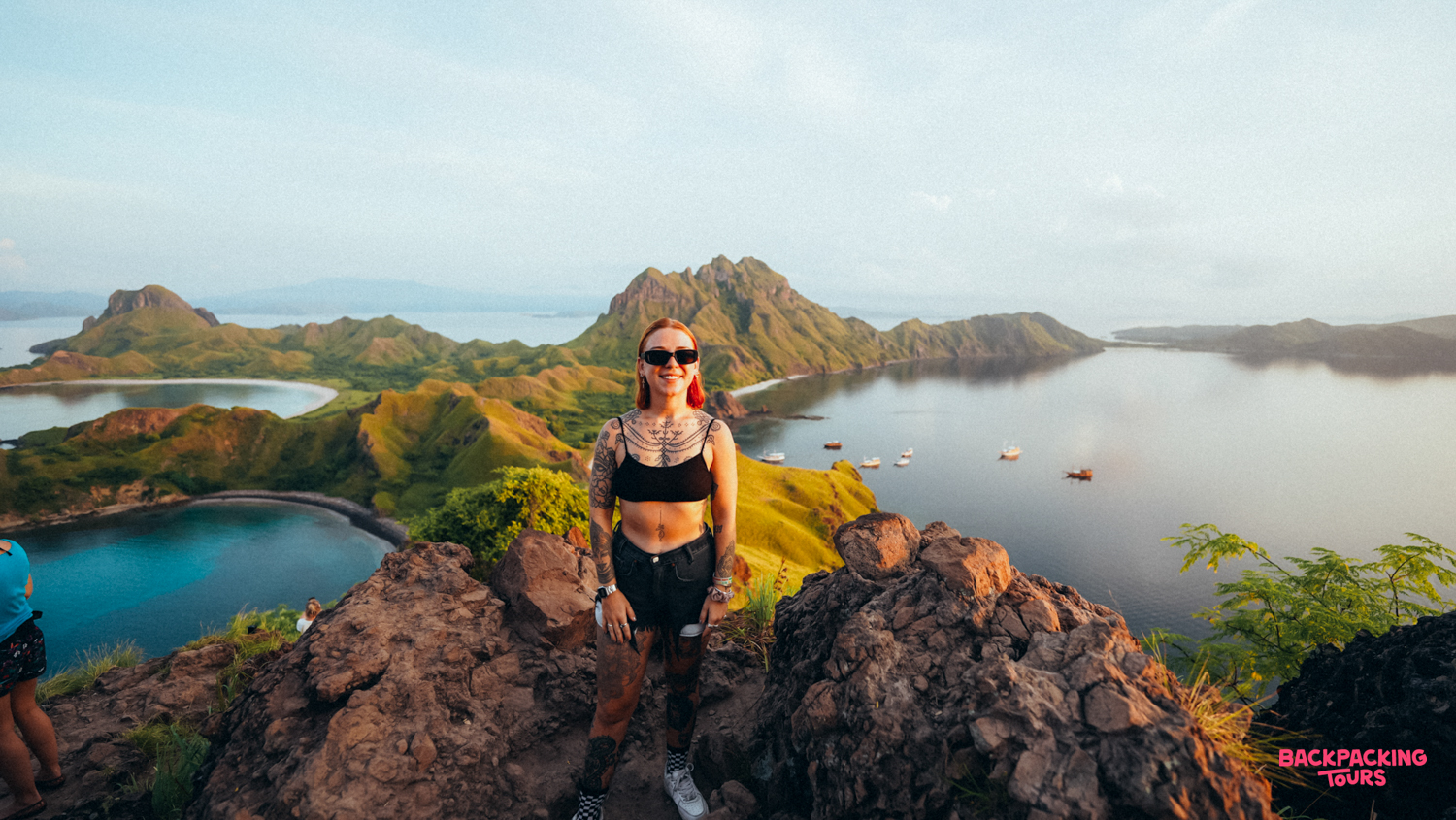 Smiling woman on a rocky viewpoint overlooking the iconic multi-bay landscape of Padar Island.