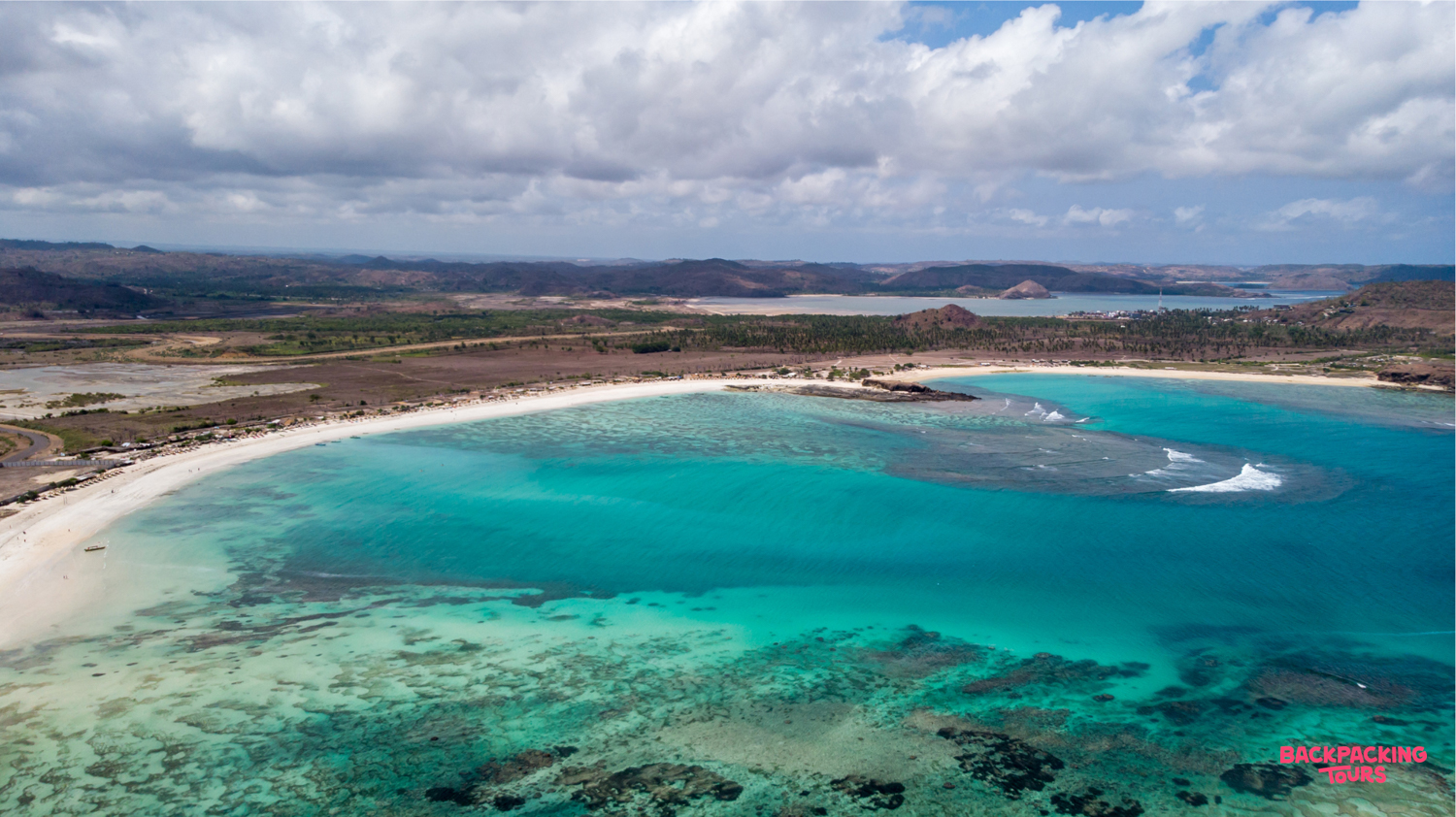 Lombok's stunning white sand beach and clear turquoise waters with visible coral reefs from above.