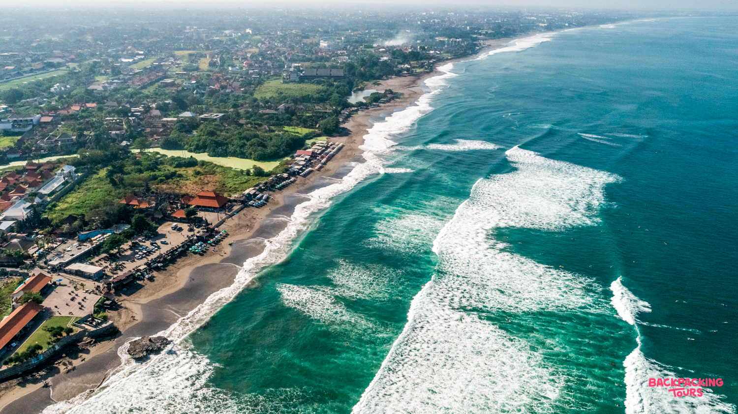Aerial view of the vibrant Kuta Lombok coastline, where turquoise waves meet the bustling town.