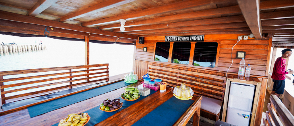Snacks on wooden tables on a liveaboard boat deck, with a man looking out at Satonda Island.