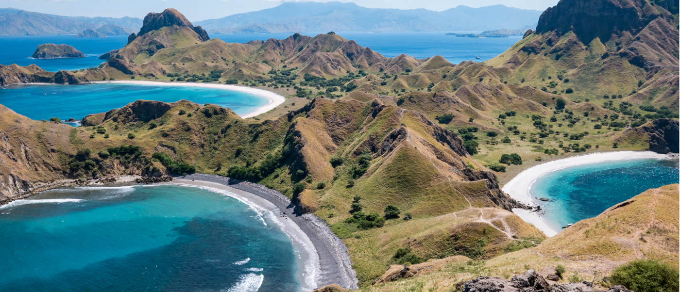Panoramic view of Padar Island's unique landscape with three distinct bays and rolling hills.