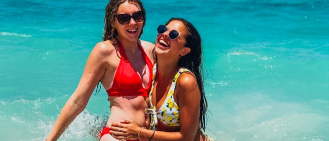 Two happy women laughing and splashing in the clear turquoise waters of Lombok.