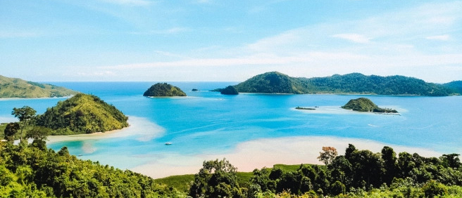 Panoramic view of small green islands in the vibrant blue ocean at Sungai Pinang, Indonesia.