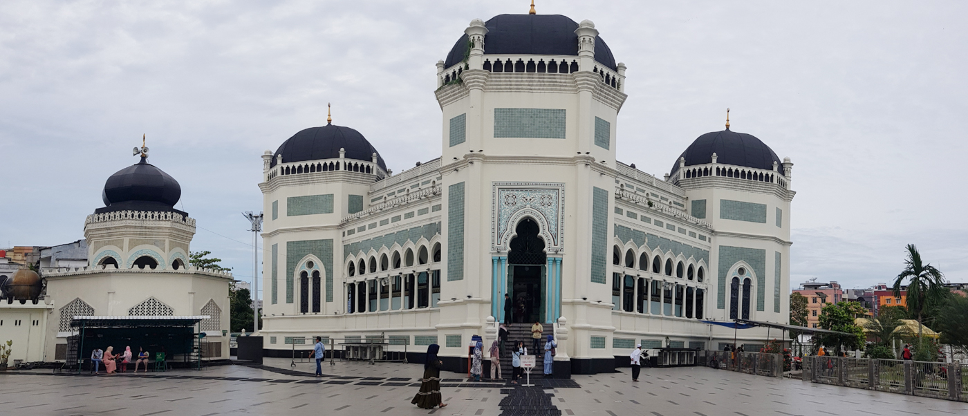 The majestic Al-Mashun Mosque in Medan, Indonesia, with its distinctive black domes and light walls.