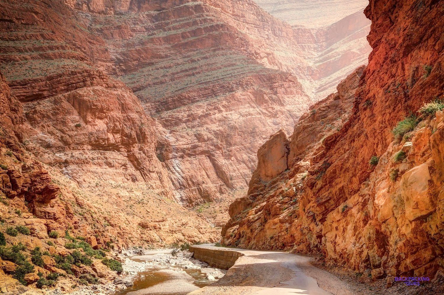 A dry riverbed winds between steep red cliffs at the entrance to Todra Gorge.
