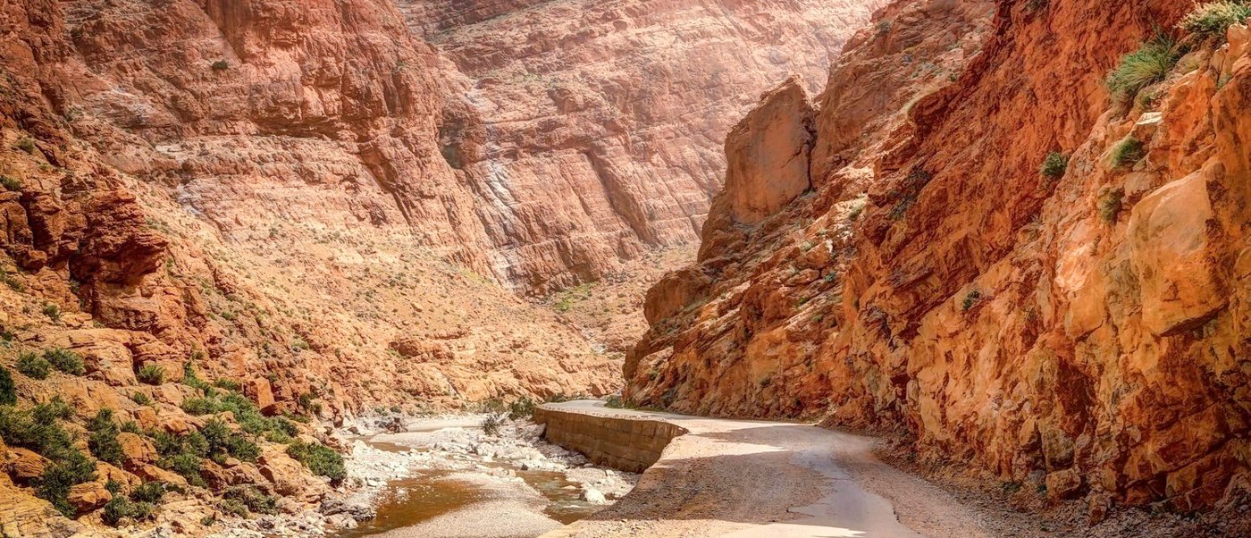 A dry riverbed winds between steep red cliffs at the entrance to Todra Gorge.