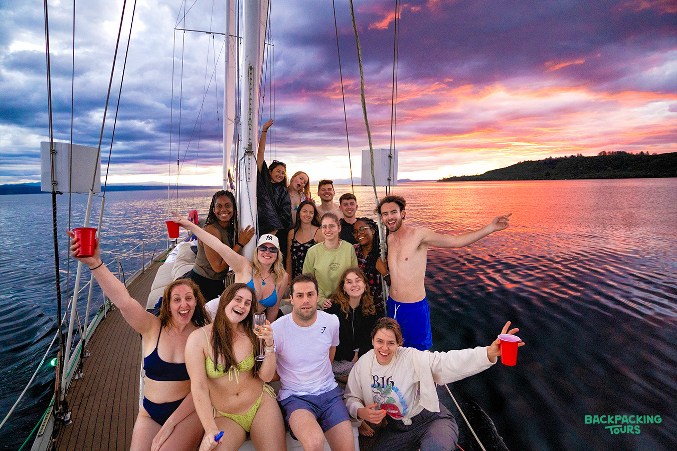 A group of happy backpackers enjoying a beautiful sunset cruise on Lake Taupo, New Zealand.