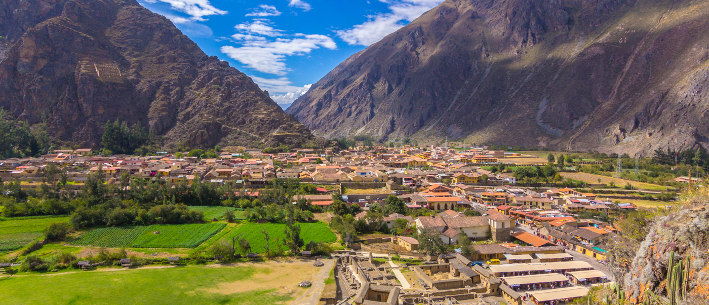 Historic Ollantaytambo town nestled in a valley, surrounded by ancient ruins and majestic mountains.