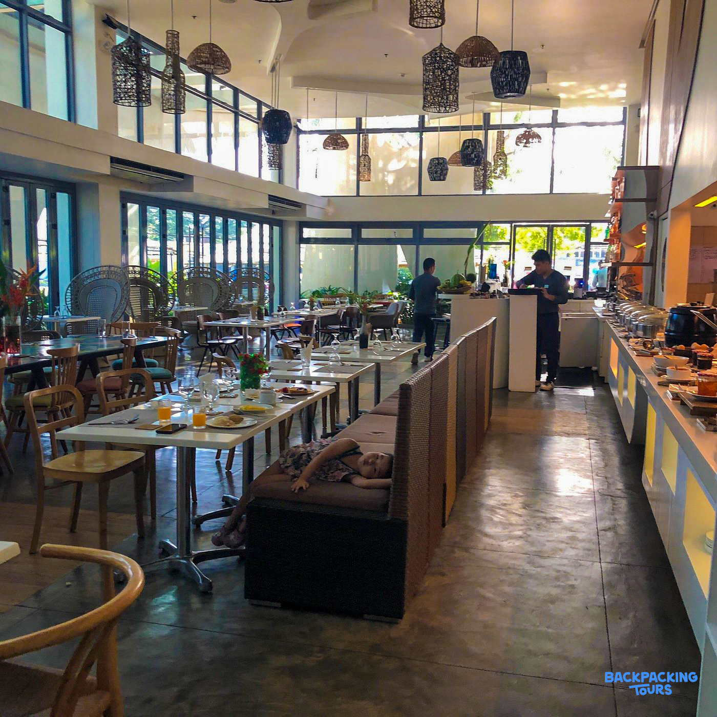 A spacious hotel dining room in Puerto Princesa where a guest relaxes after a leisurely breakfast.