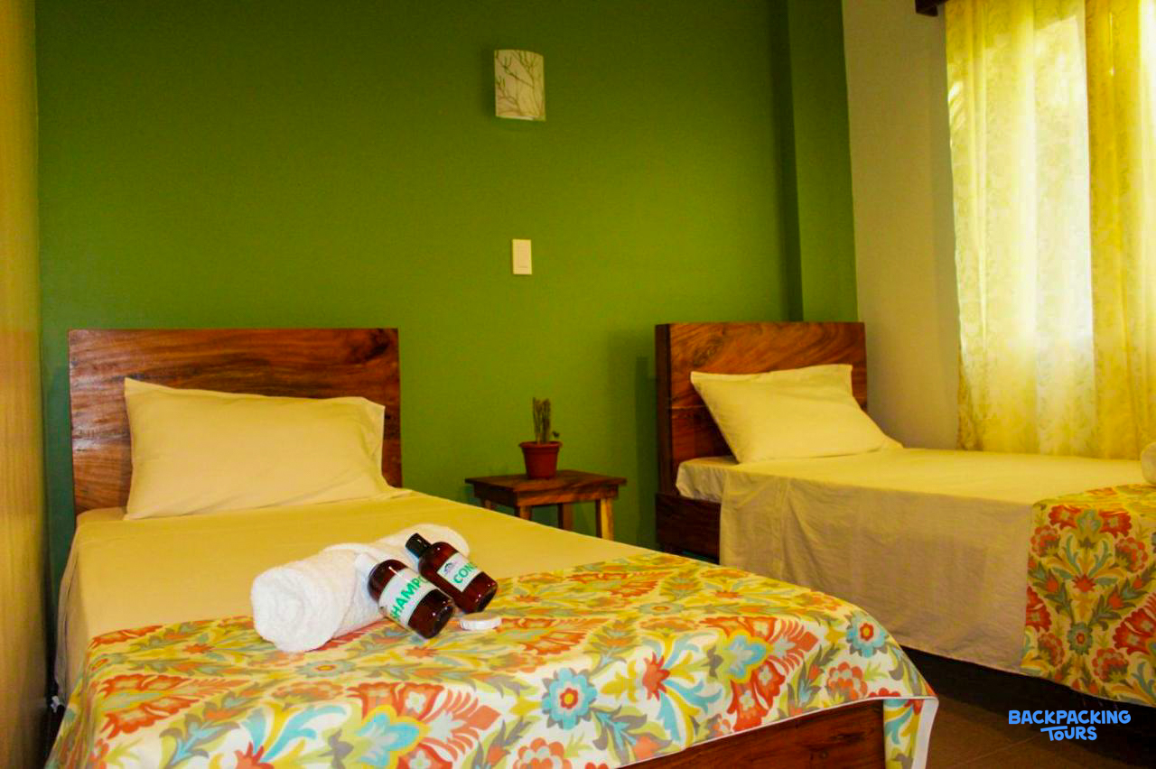 A vibrant green room with two comfortable single beds and colorful floral bedspreads in Coron.