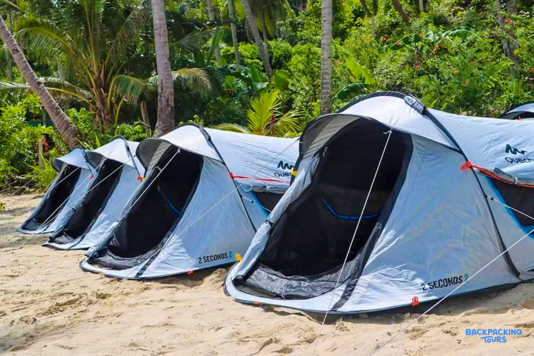 Four pop-up tents pitched on a sandy beach, ready for island camping in Port Barton.