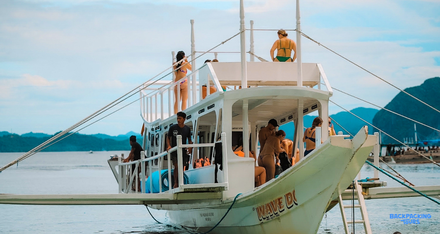 Backpackers on a traditional Philippine boat cruising through the scenic waters of El Nido, Philippines.