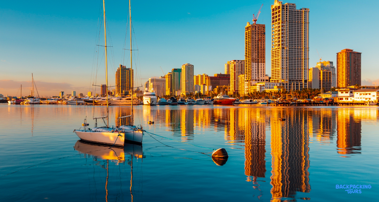 Golden hour over Manila Bay, with yachts reflecting in the calm water against the city skyline.