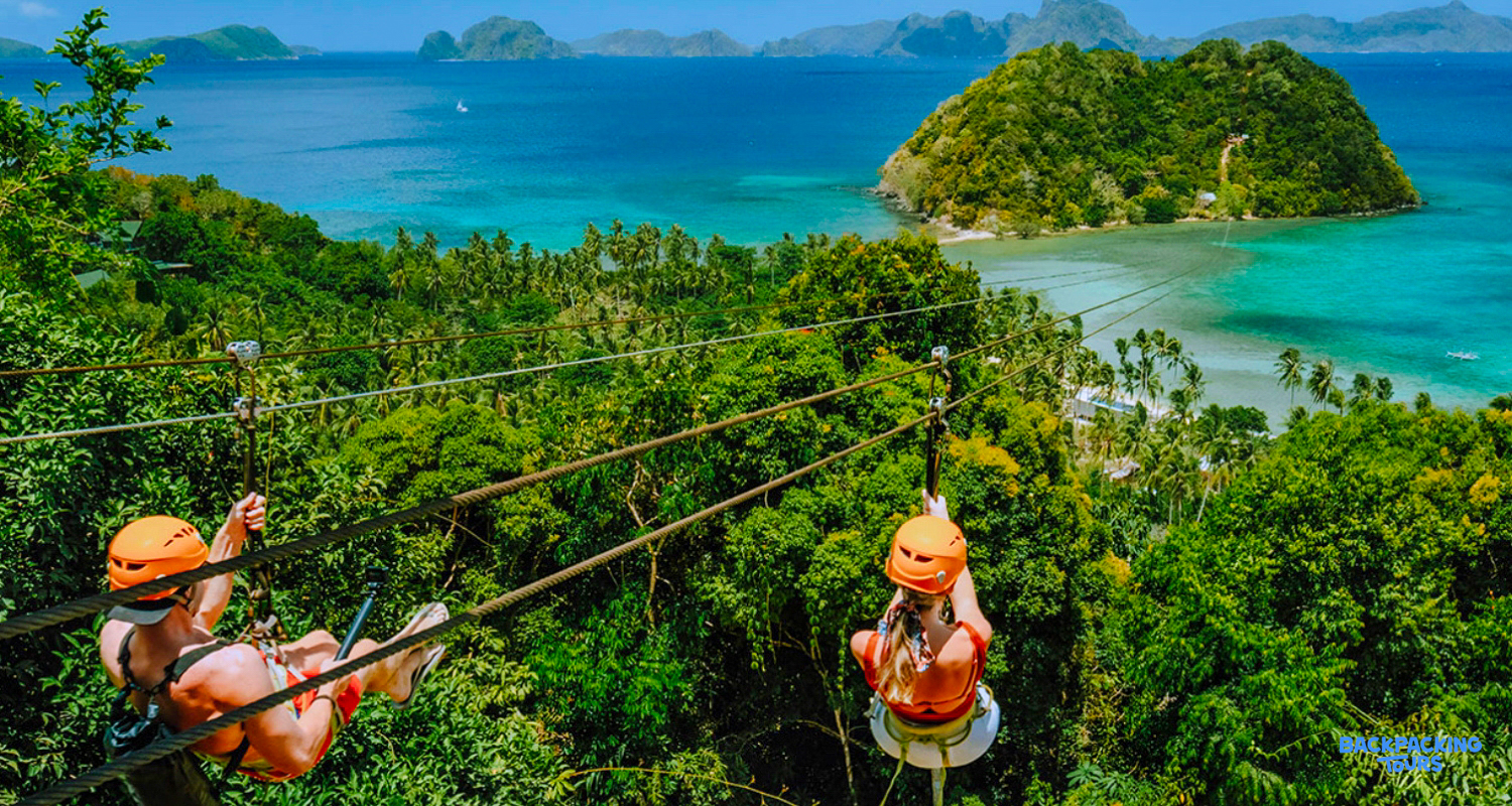 Two adventurers zipline high above the lush green canopy, overlooking El Nido's stunning turquoise bay and islands.