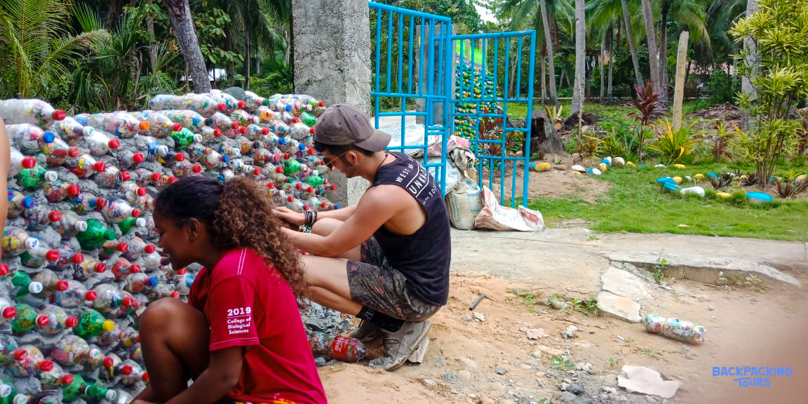 Volunteers diligently construct an eco-brick wall from recycled plastic bottles in the Philippines.
