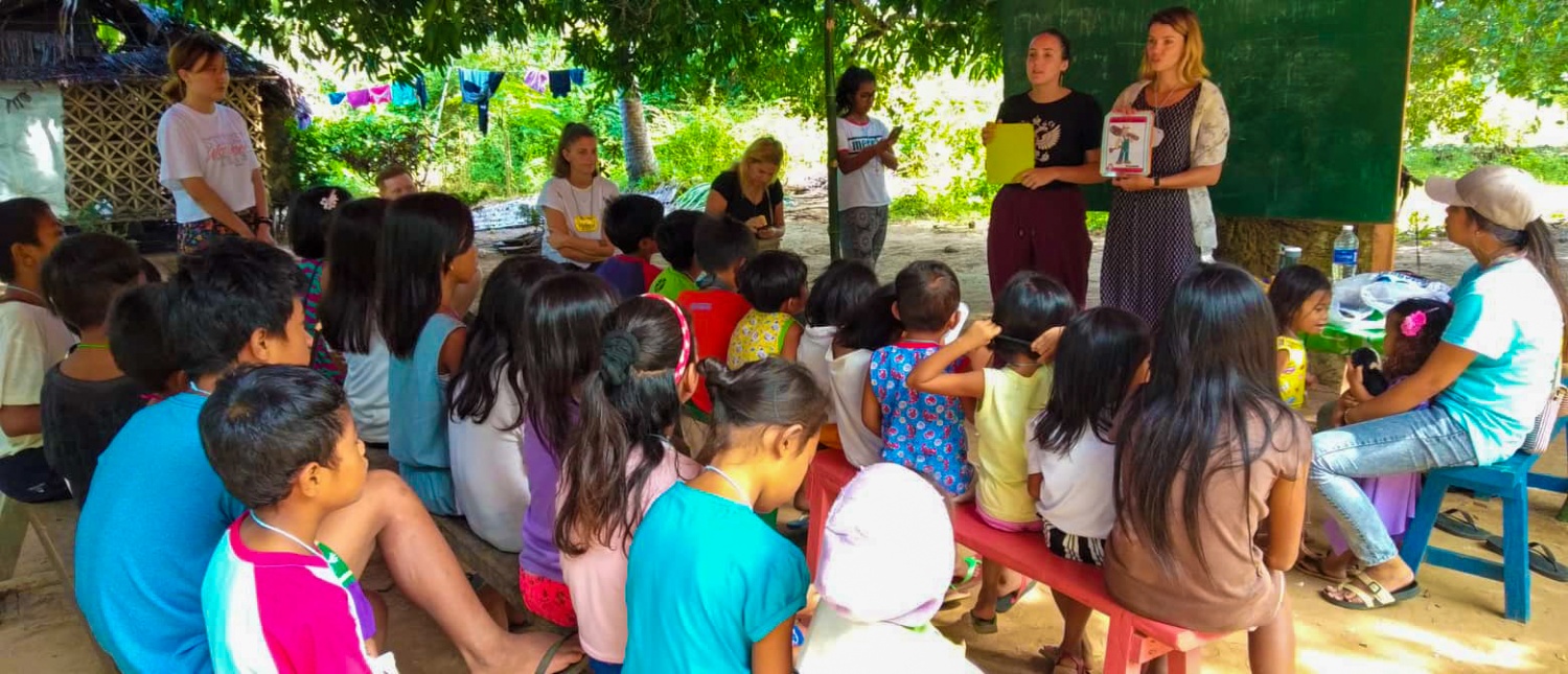 Volunteers teach a group of children about environmental conservation outdoors in a rural Philippine community.