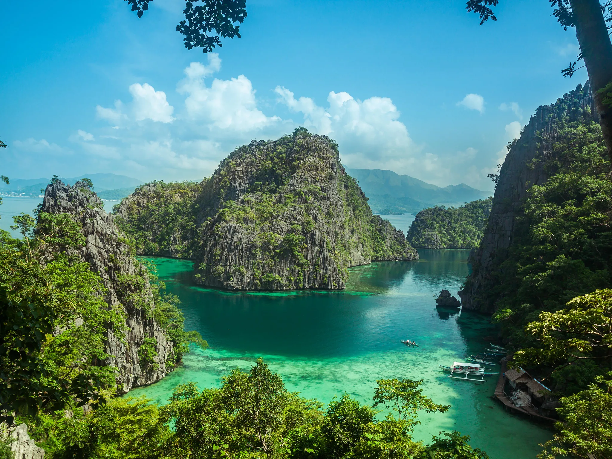 Lush green limestone islands rise from clear turquoise waters in a beautiful bay, Palawan, Philippines.
