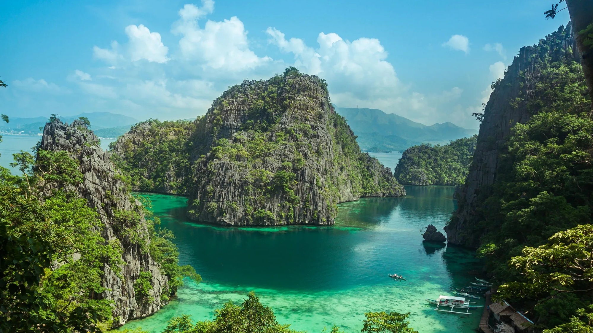 Stunning turquoise lagoon surrounded by towering green limestone karsts in Coron, Palawan, Philippines.