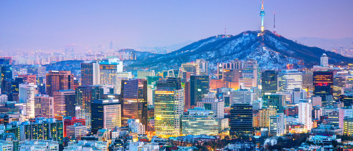 Seoul's vibrant cityscape at twilight, with illuminated skyscrapers and Namsan mountain topped by N Seoul Tower.