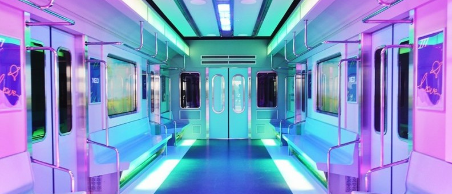 An empty, futuristic Seoul subway car interior glowing with vibrant neon pink, blue, and green lights.