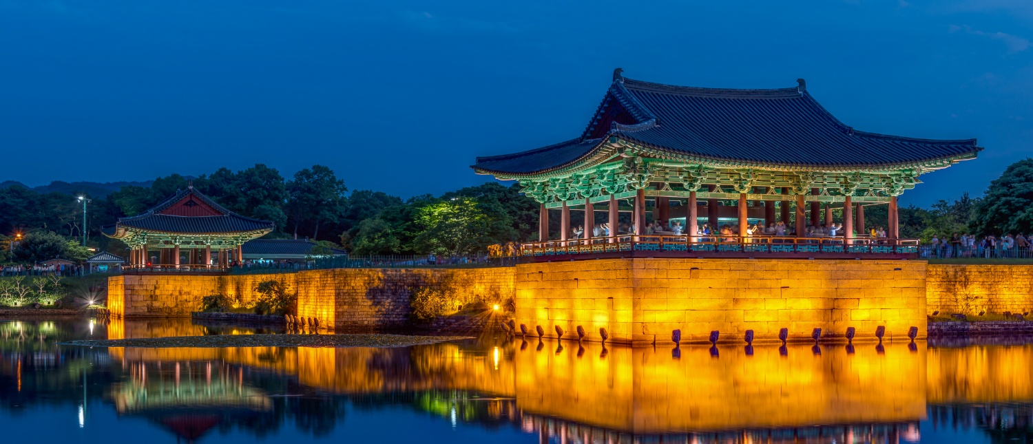 Illuminated traditional Korean pavilions reflect in Anapji Pond at night, creating a serene scene in Gyeongju.