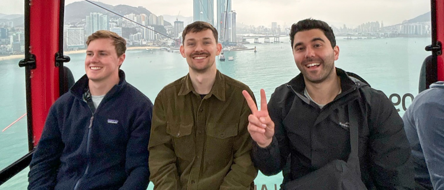Three happy men ride the Songdo cable car, enjoying panoramic city and ocean views in Busan.