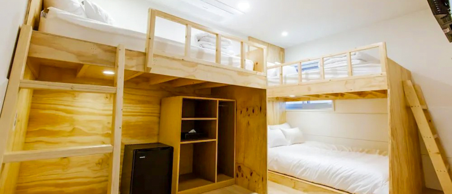 A cozy hostel room in Seoul with light wood bunk beds, a single bed, and storage.