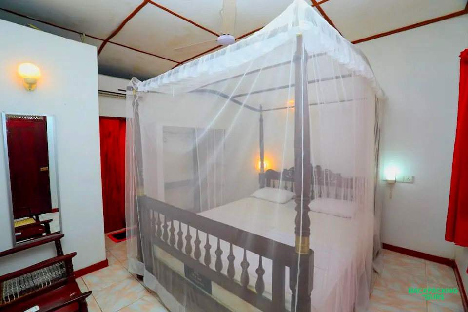 A comfortable bedroom in Mirissa with a four-poster bed and mosquito net, perfect for relaxing.