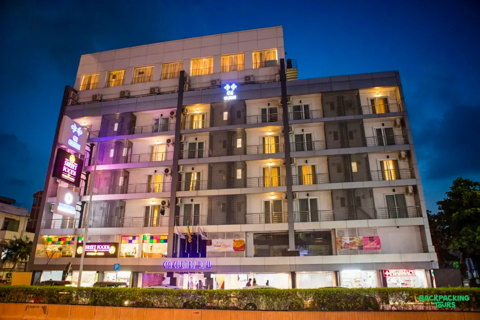 A modern multi-story hotel building with many lit windows at dusk in Nuwara Eliya.