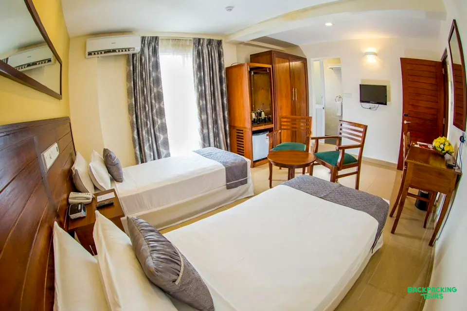 A comfortable twin room with two beds, a small table, and a wardrobe in Nuwara Eliya.