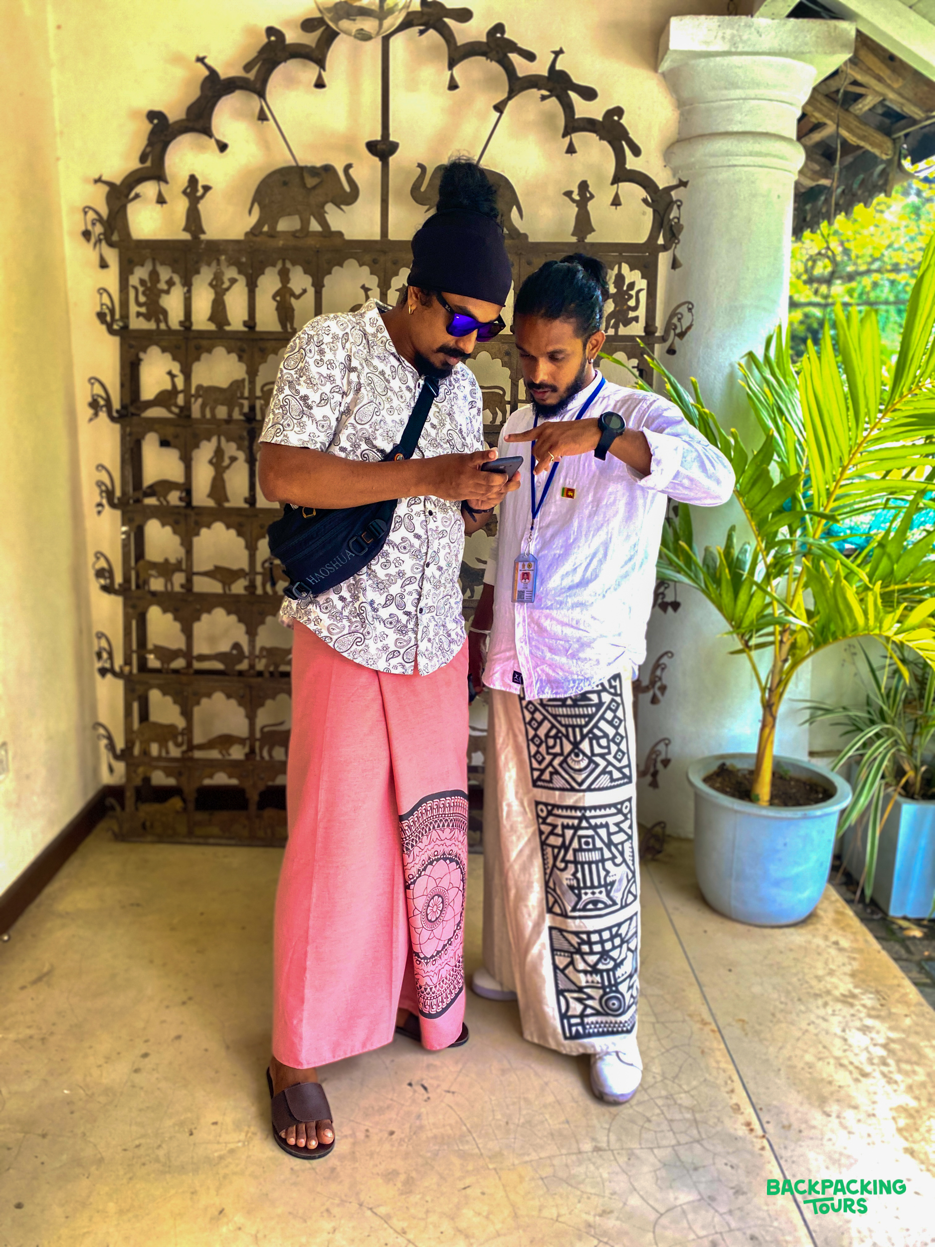 Two men in patterned sarongs look at a phone in Kandy, Sri Lanka.