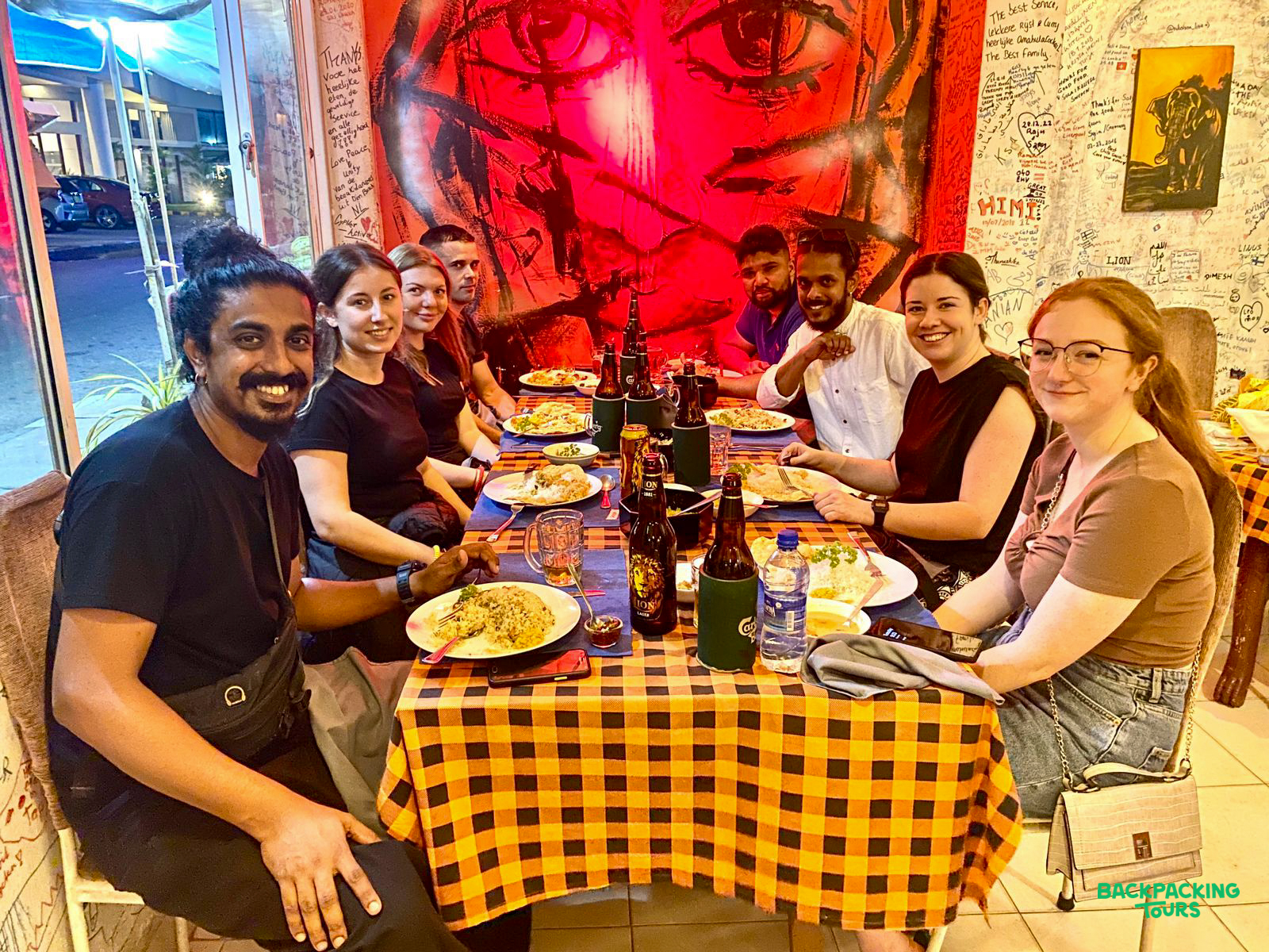 Eight happy backpackers enjoying a welcome dinner at a vibrant restaurant in Colombo.