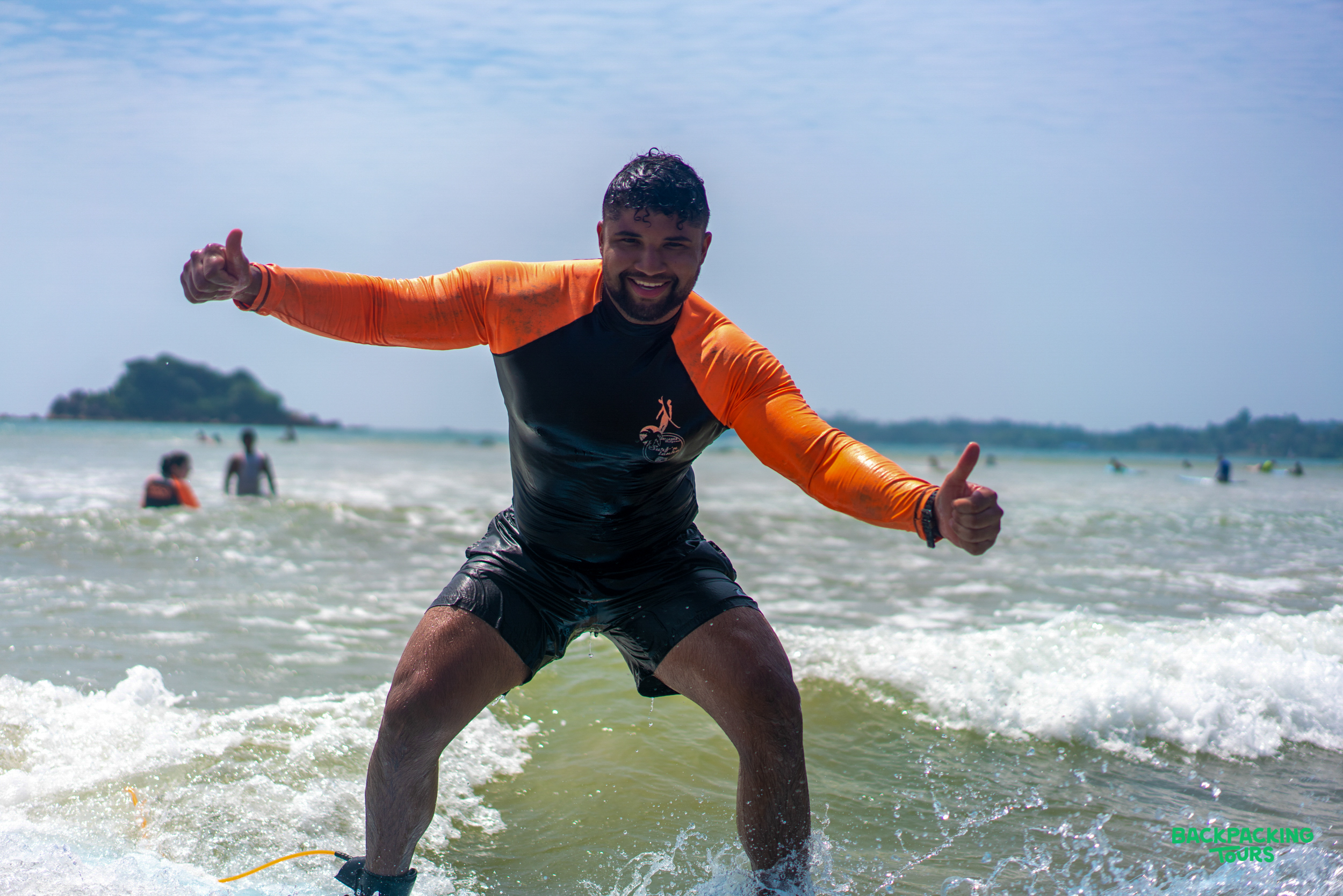 A happy man on a surfboard gives thumbs up, enjoying his surf lesson at Weligama Beach.