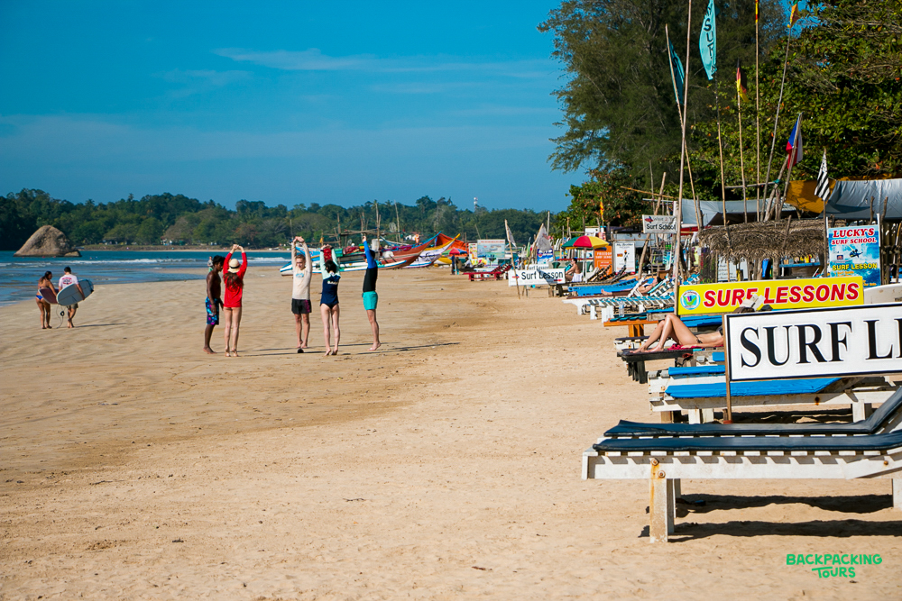 People stretch and relax on a sunny Mirissa beach, with surf lessons and loungers available.