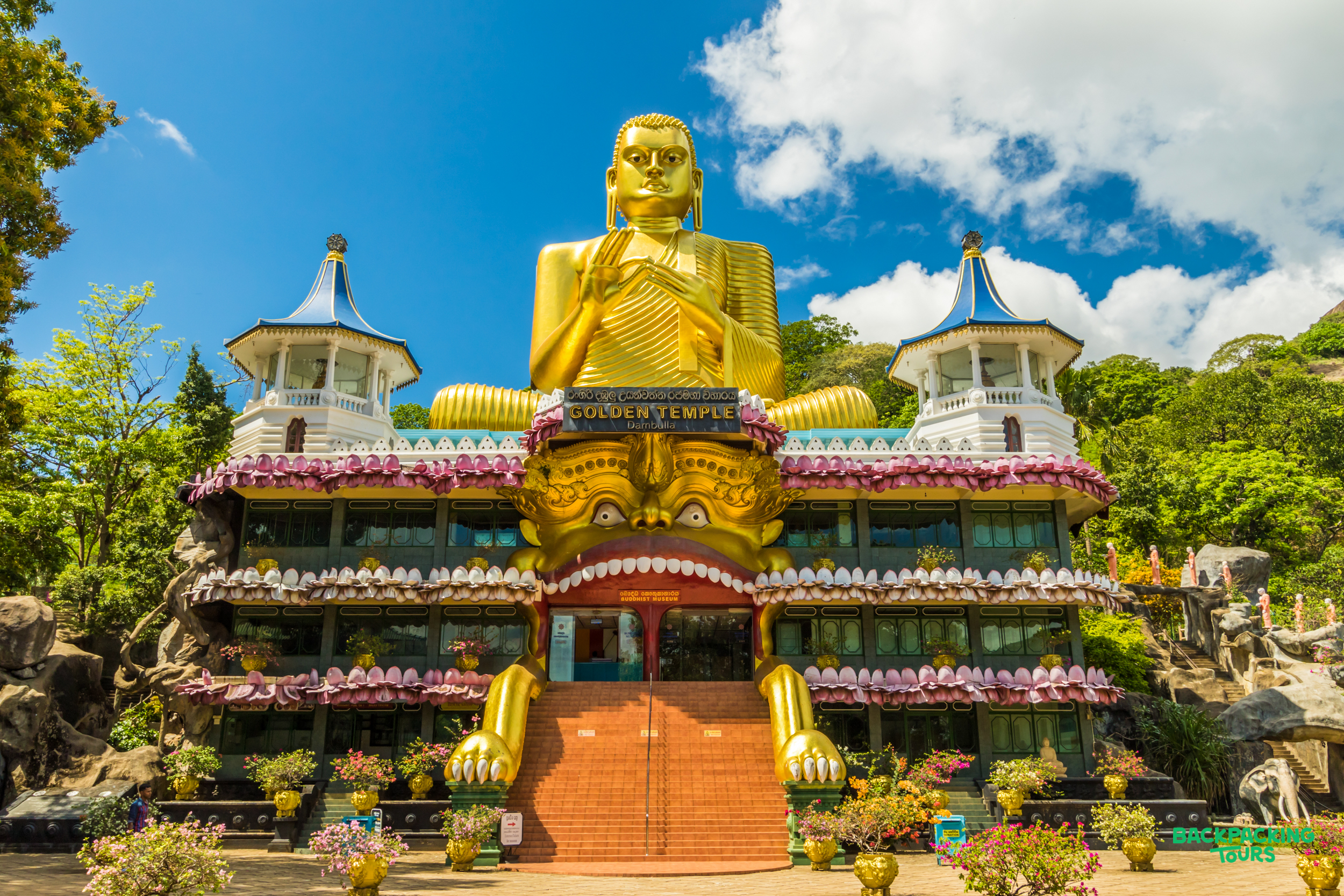 A towering golden Buddha statue sits atop the ornate Golden Temple of Dambulla, Sri Lanka.