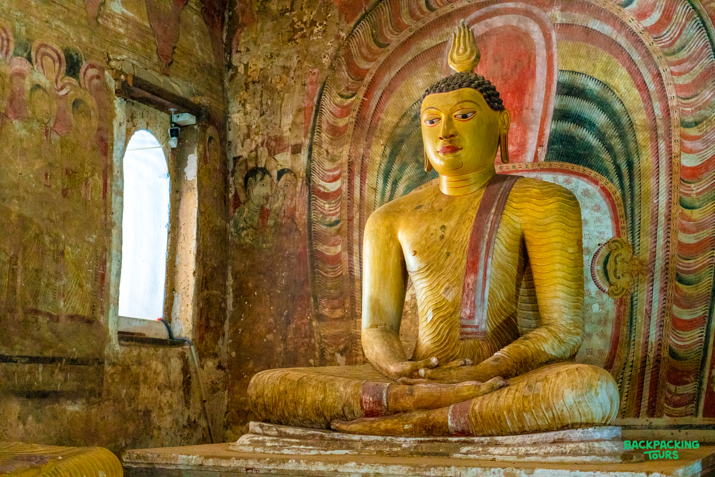 A golden Buddha statue sits serenely in the ancient Dambulla Cave Temple in Sri Lanka.