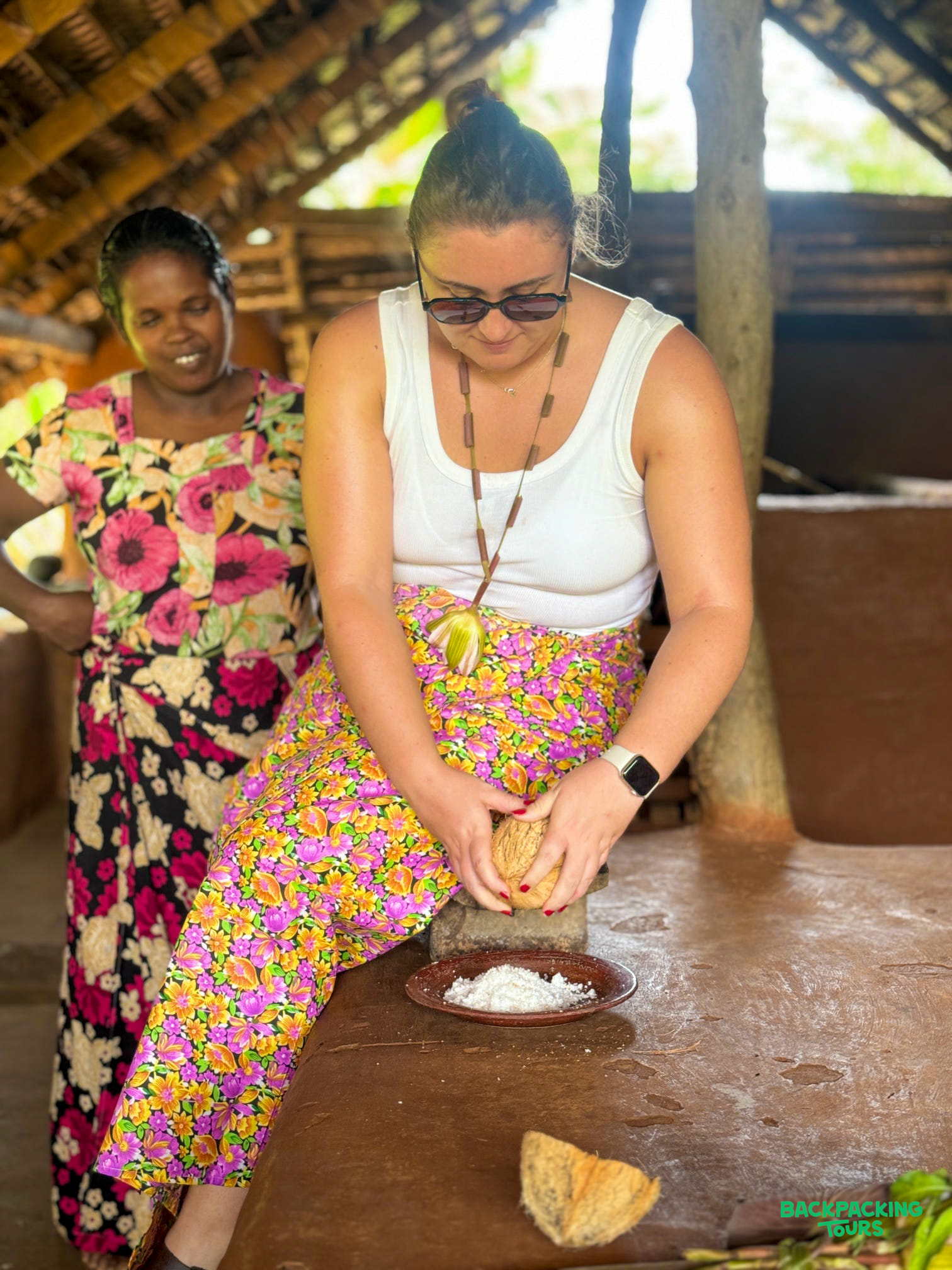 A traveler learns to grate coconut with a local woman during a village tour in Sigiriya.