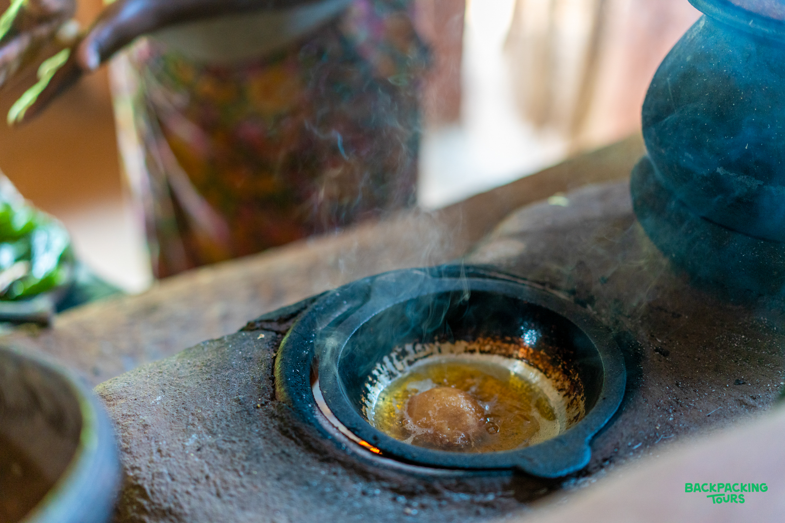 A traditional cooking pot on a rustic stove, with steam rising, preparing a meal in Kandy.