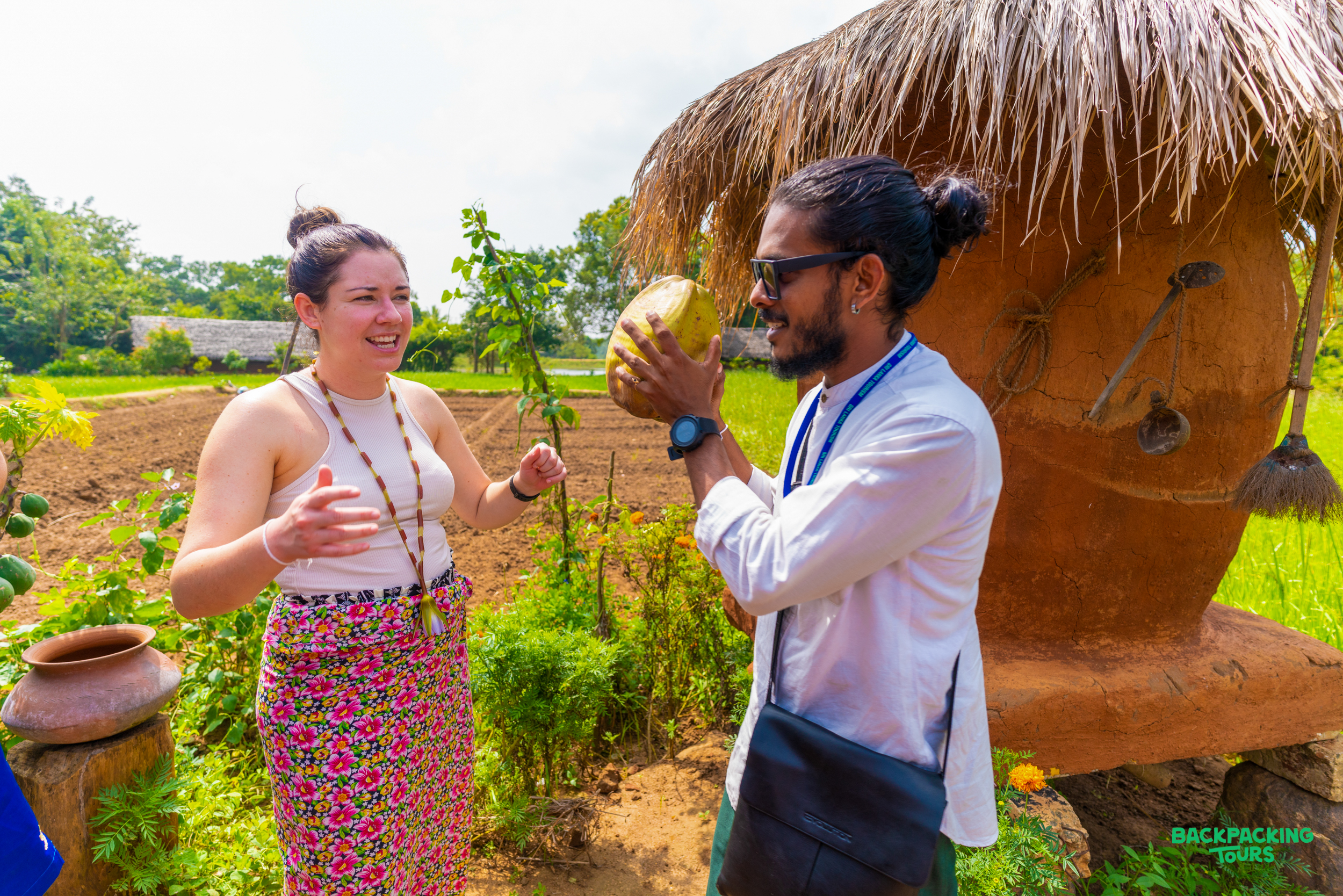 A local guide shows a tourist a fresh coconut during a cultural village tour in Kandy.
