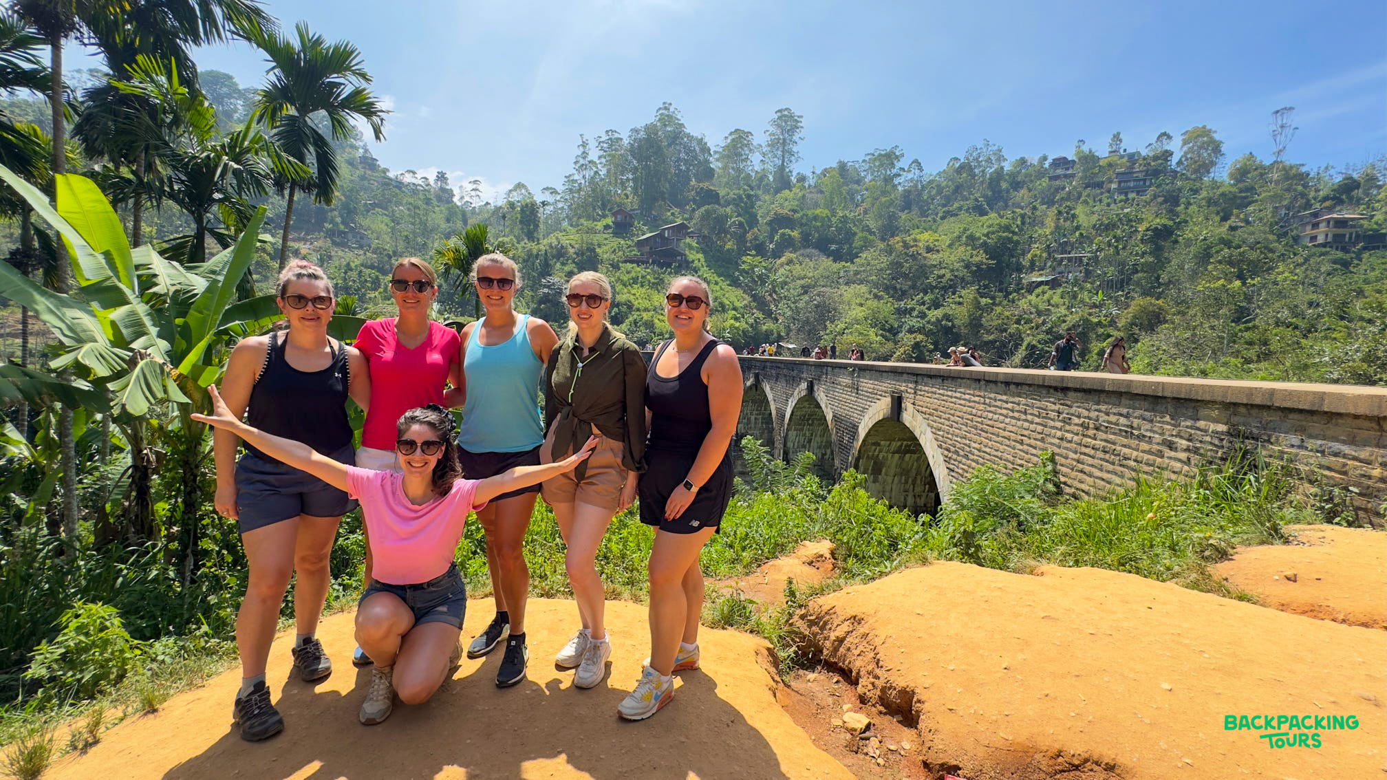Six smiling women enjoying the view of the Nine Arch Bridge in Ella, Sri Lanka.