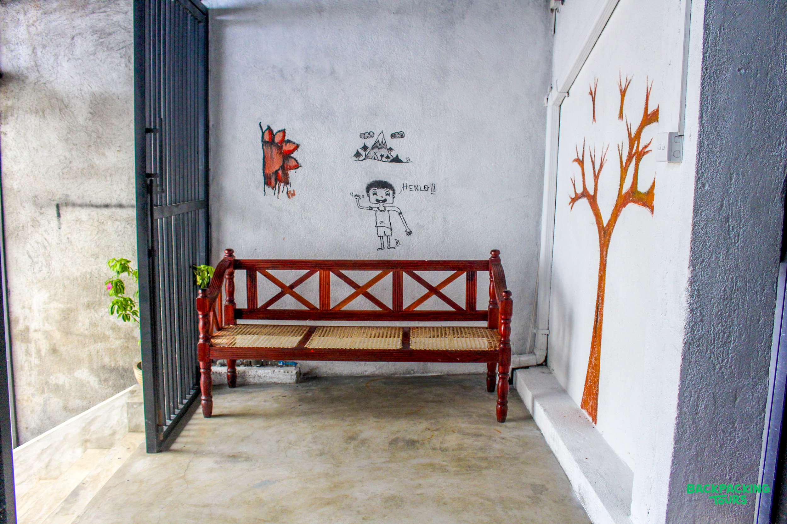 A welcoming wooden bench with playful wall art at the front gate of a home.
