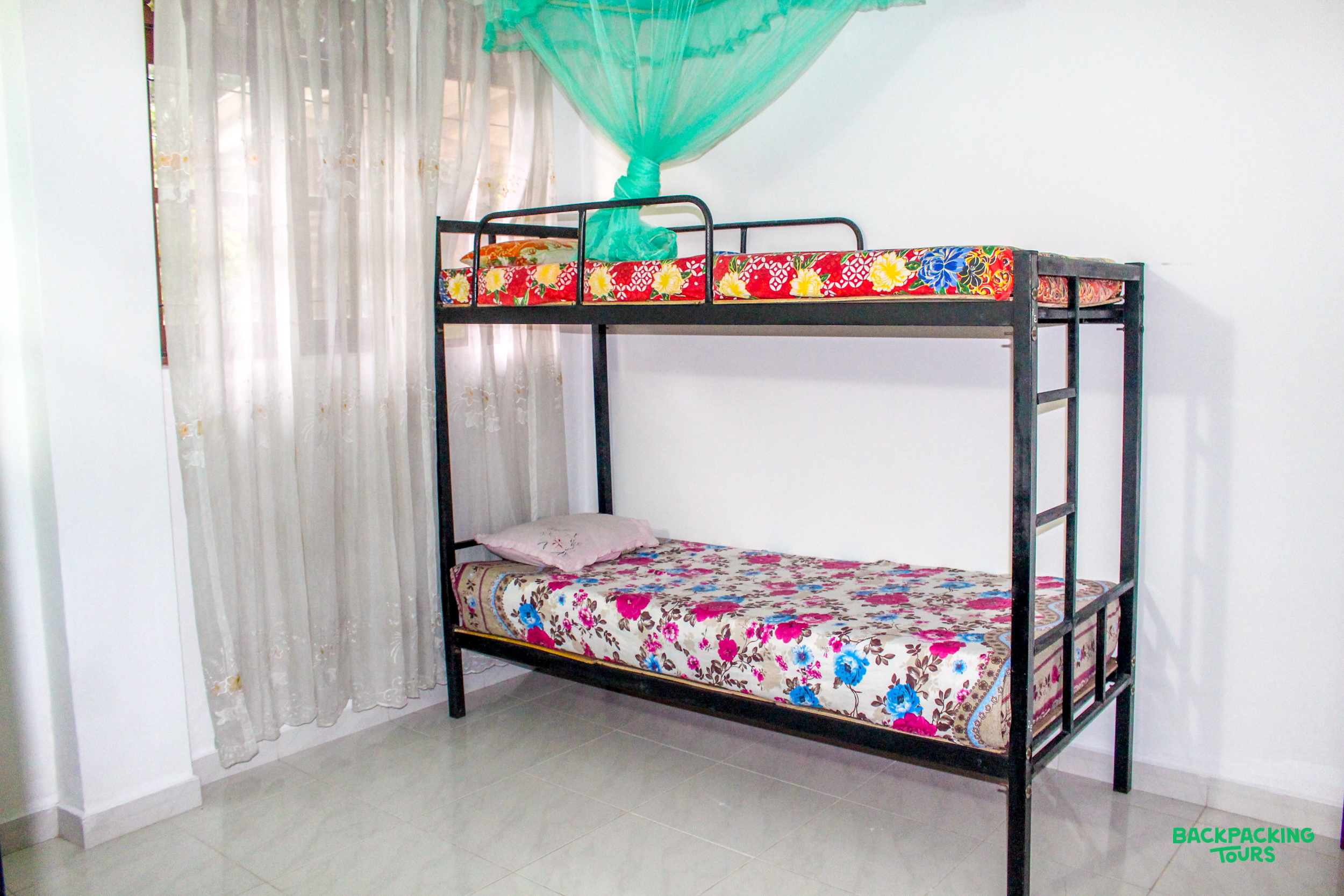 A cozy bunk bed with vibrant floral mattresses and a protective green mosquito net.