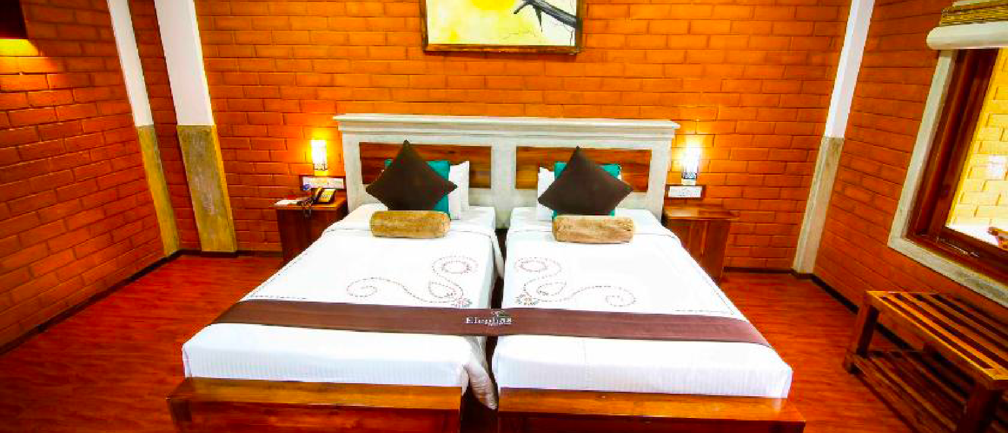 A cozy hotel room in Dambulla featuring two single beds, brick walls, and warm lighting.