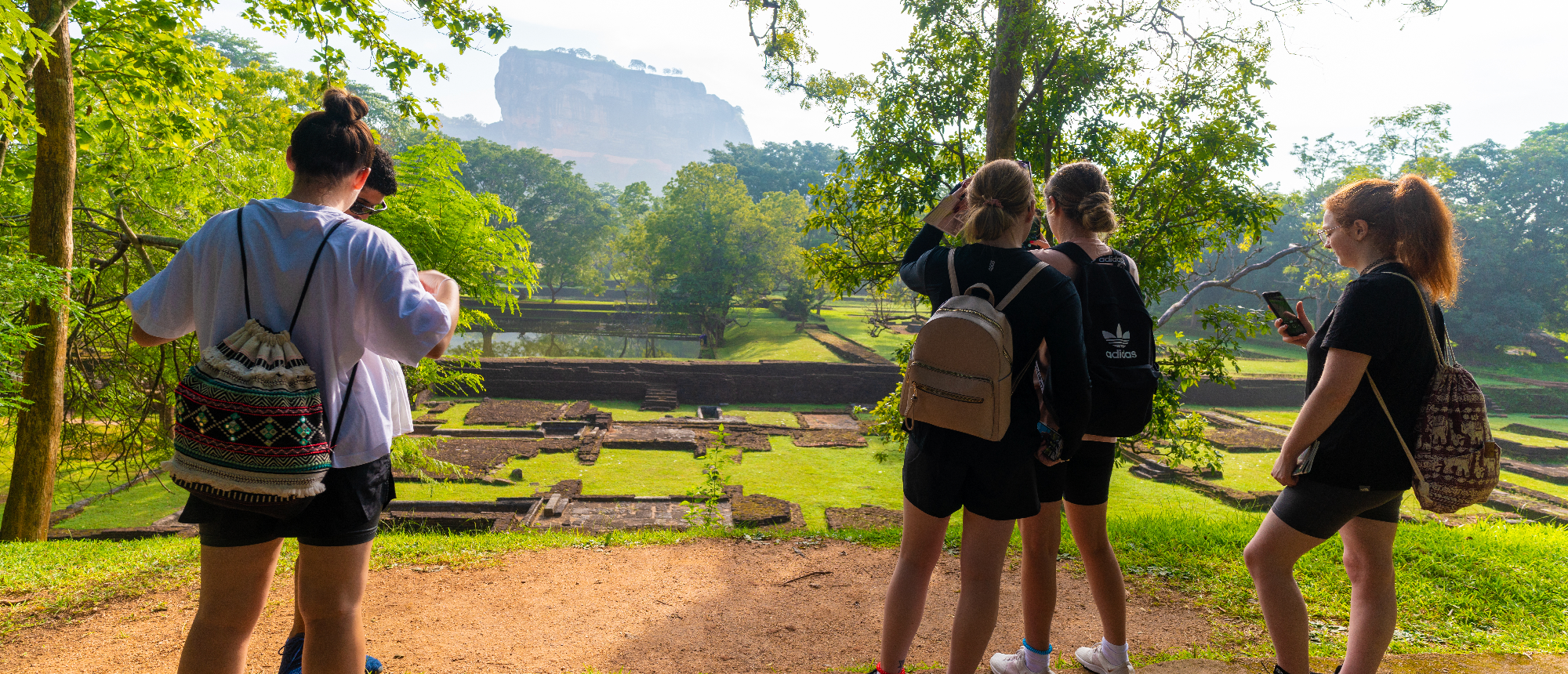 Four travelers admire the ancient ruins and majestic Sigiriya rock in Sri Lanka.