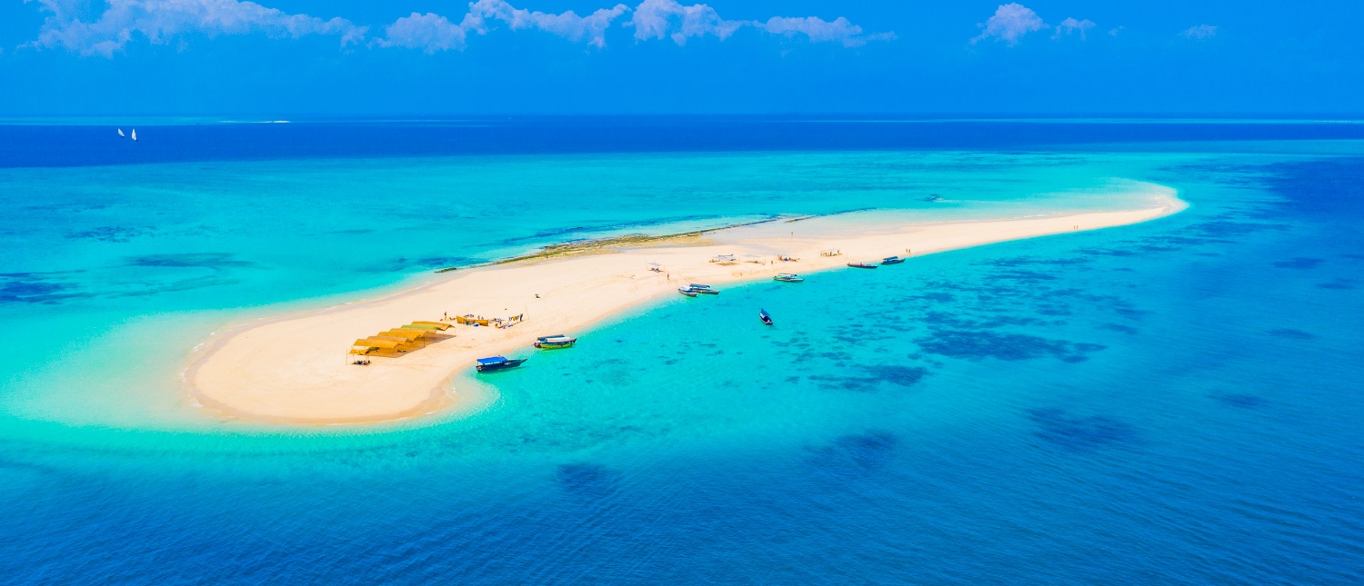 An aerial view of a pristine white sandbar surrounded by vibrant turquoise waters in Zanzibar.